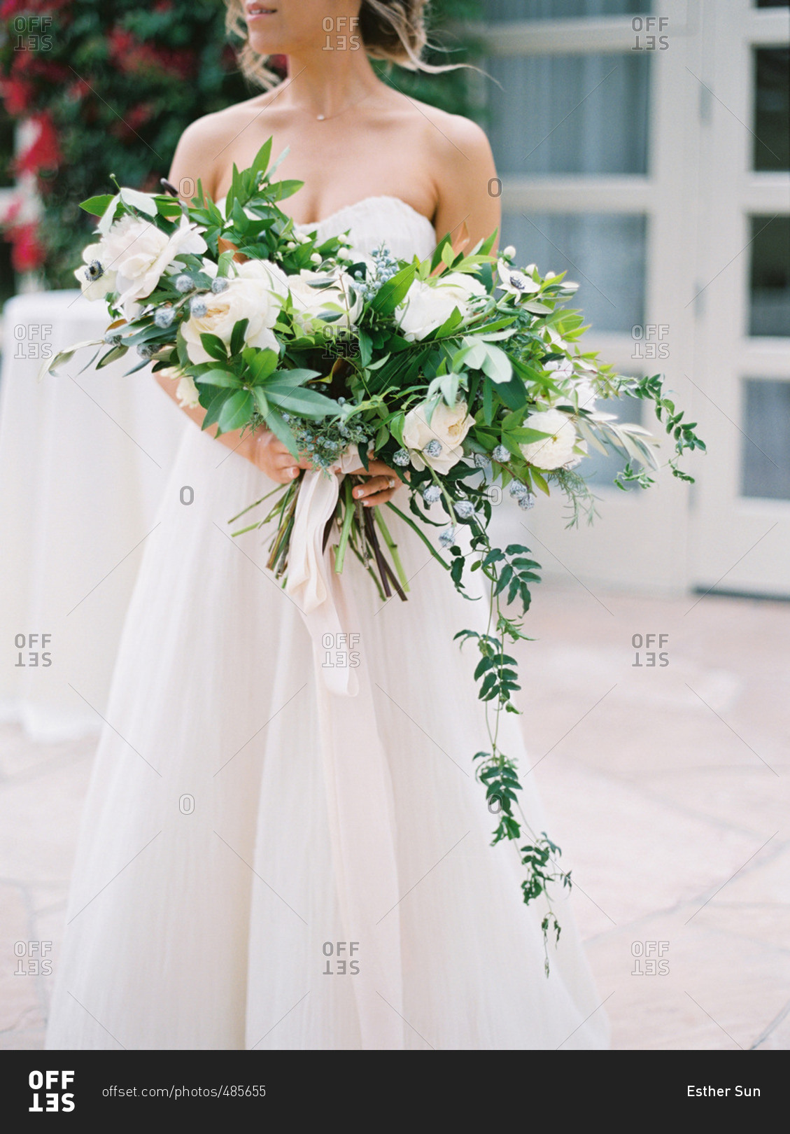 Neck down portrait of seated bride with white and green floral bouquet
