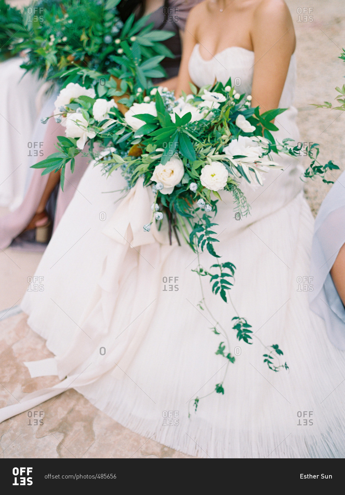 Neck down portrait of seated bride with white and green floral bouquet