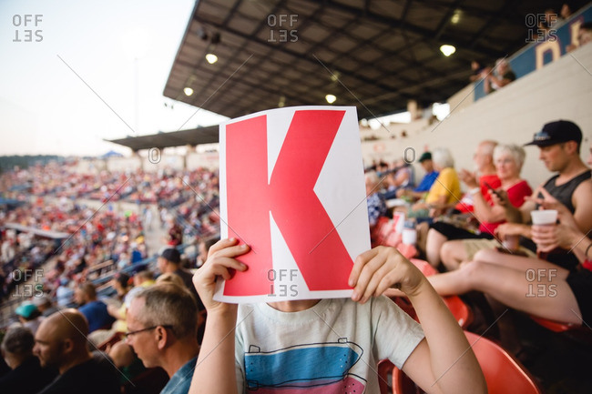 Child with a paper with letter in stands of sporting event