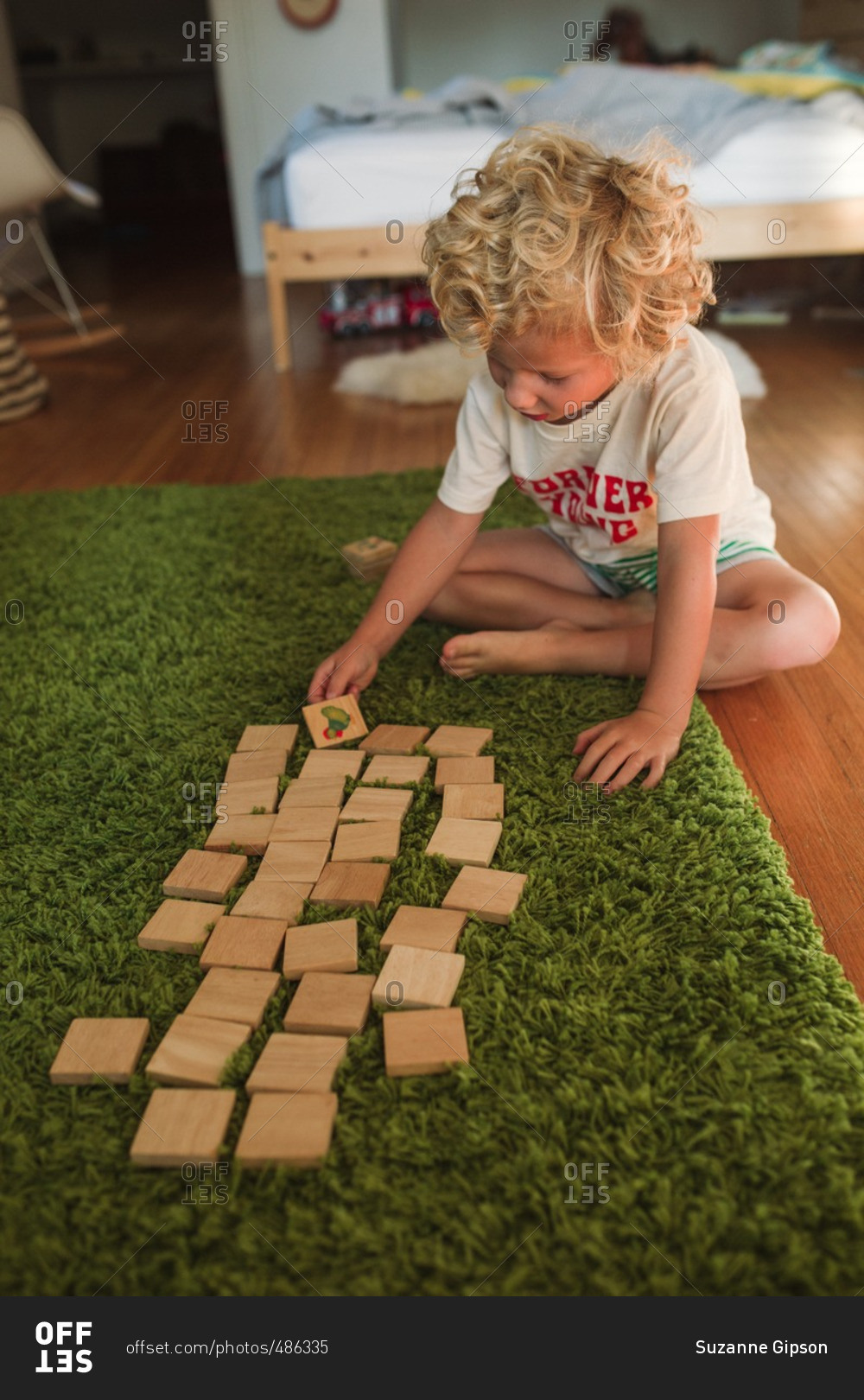 Boy playing wooden memory game on a green rug