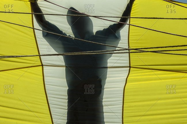 A parasailing crew member is silhouetted holding a parachute preparing to lift a client skyward off the Vietnamese coast of Nha Trang