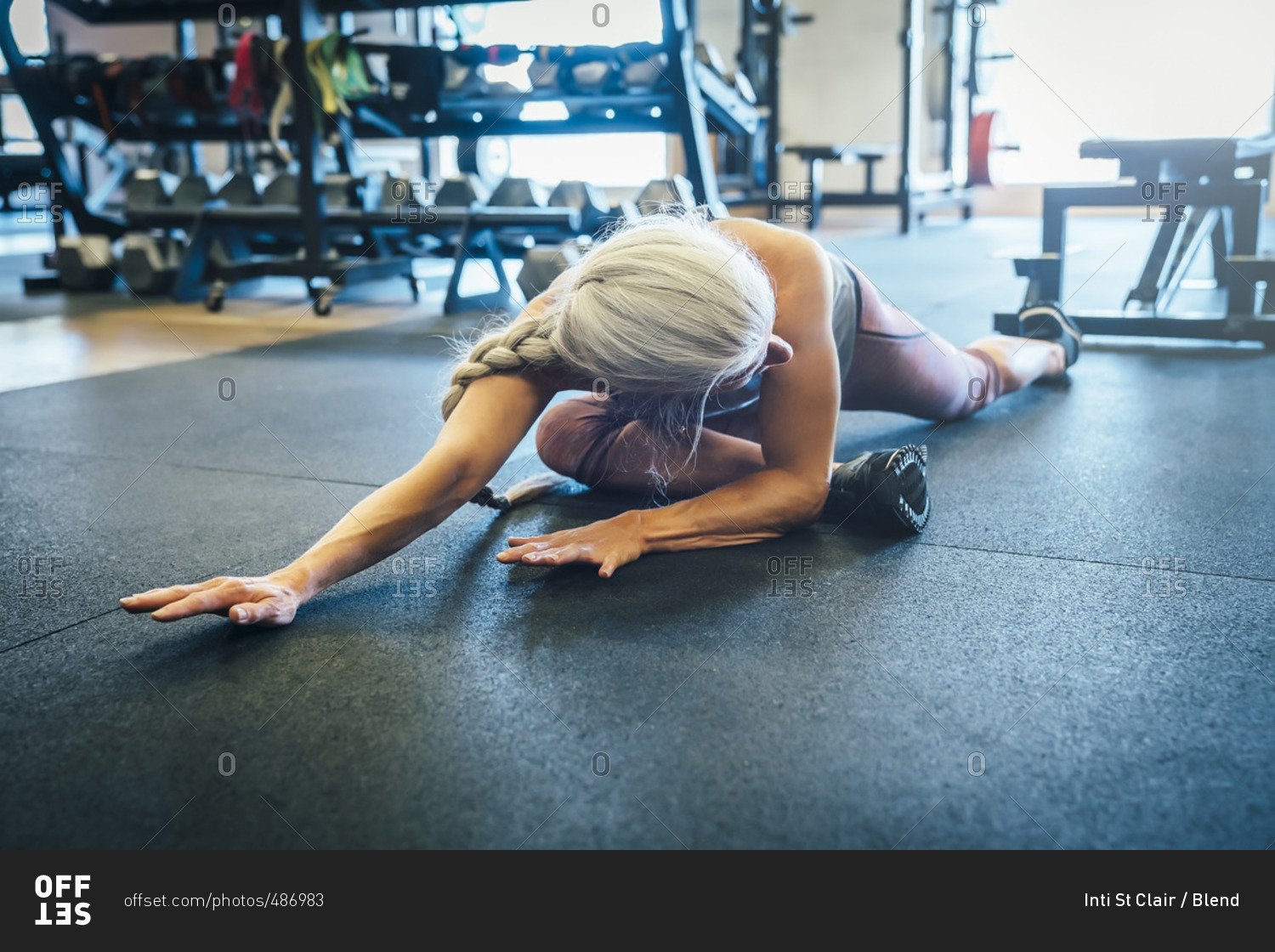 Caucasian woman stretching on gymnasium floor