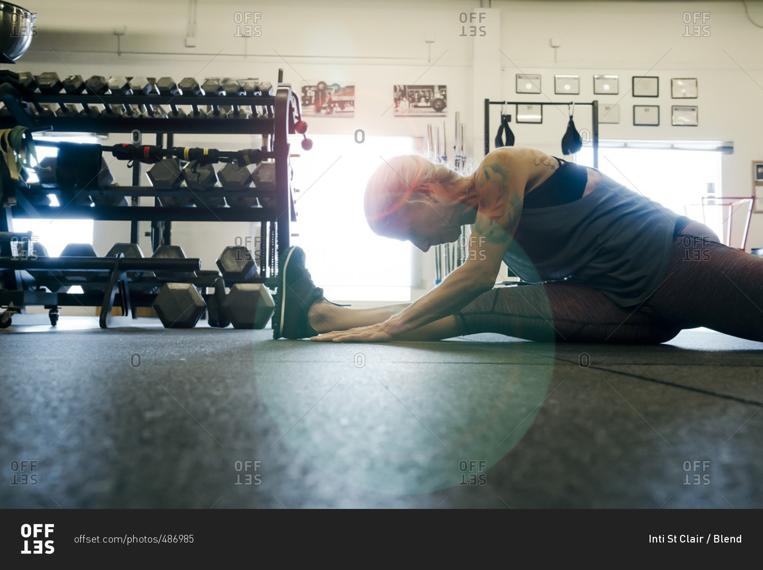 Caucasian woman stretching leg on gymnasium floor