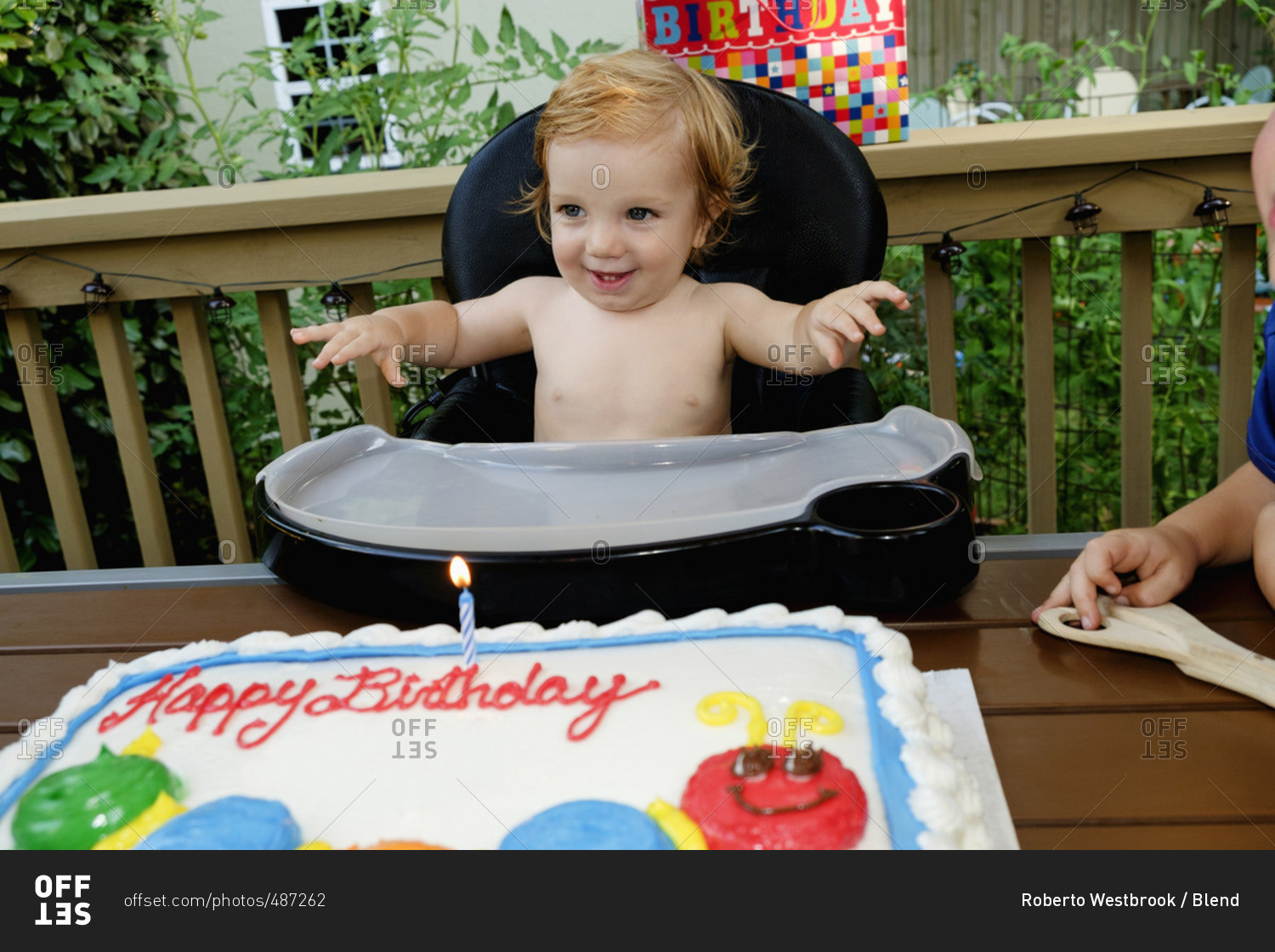 Caucasian baby boy in high chair near birthday cake