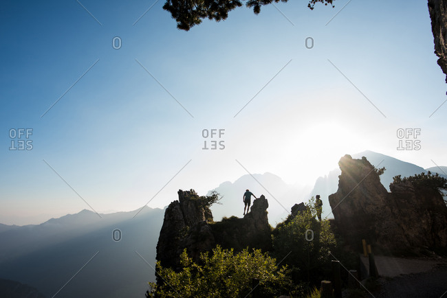Silhouettes of distant couple on mountain peak, Passo Maniva, Italy