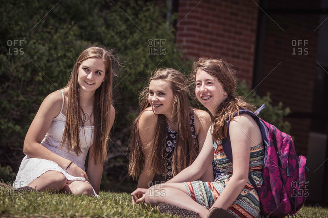 Female high school students sitting on grass outside high school