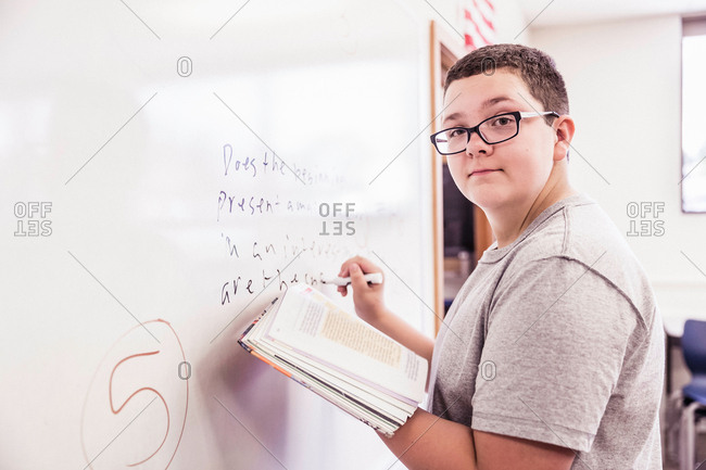 Portrait of schoolboy writing on whiteboard in class