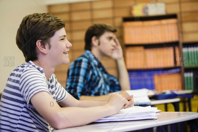 Male teenage high school students listening at desk in lesson