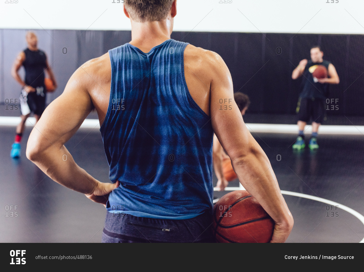Rear view of male basketball player holding ball on court