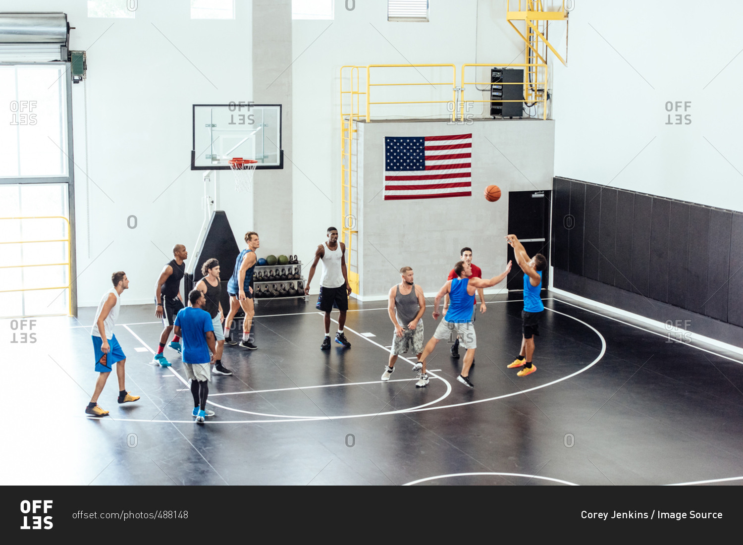 Male basketball team throwing ball into hoop on basketball court