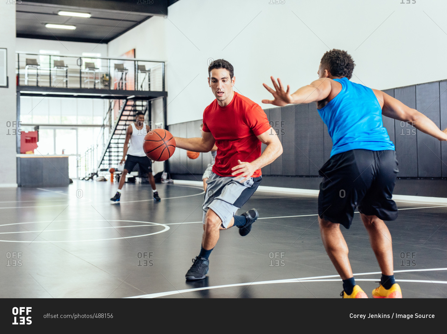 Two male basketball players practicing running and defending ball on basketball court