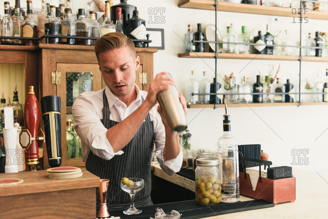 Bartender shaking cocktail shaker in cocktail bar