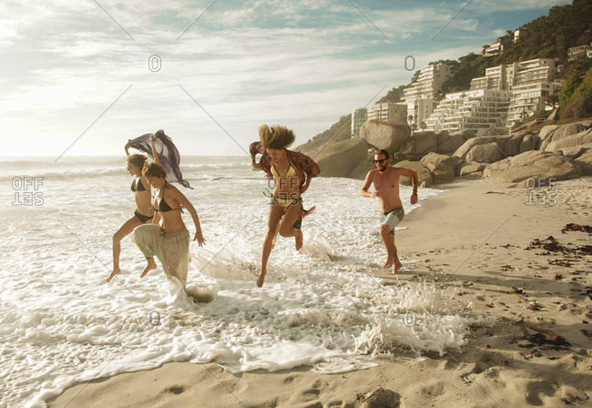 Group of friends running on beach