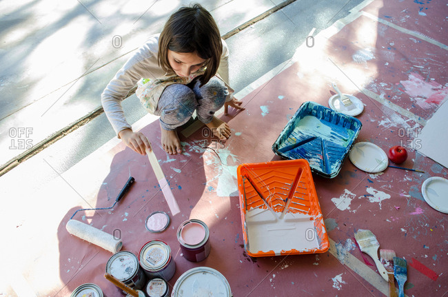 Girl in garage stirring paint in paint tins