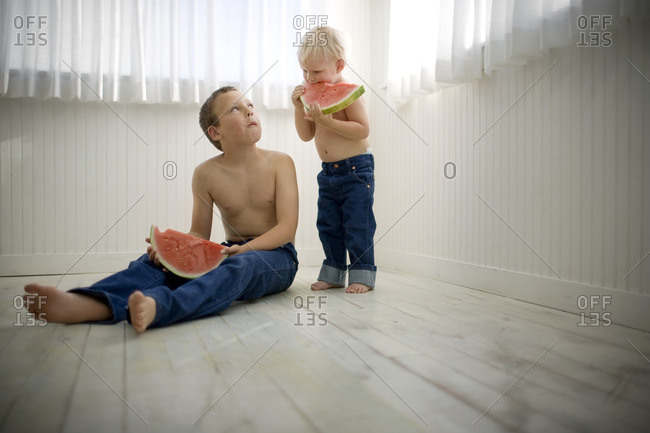 Two young brothers eating watermelon slices.