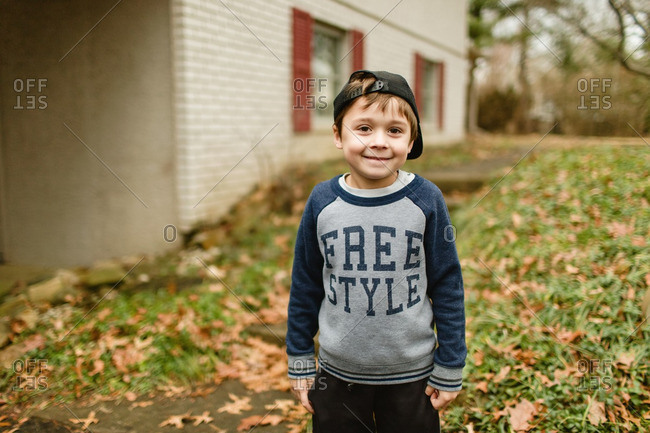 Portrait of a little boy standing outside wearing sweatshirt and baseball cap