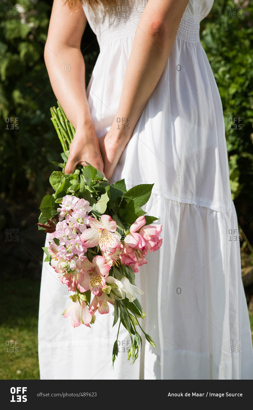 Woman holding bouquet behind back