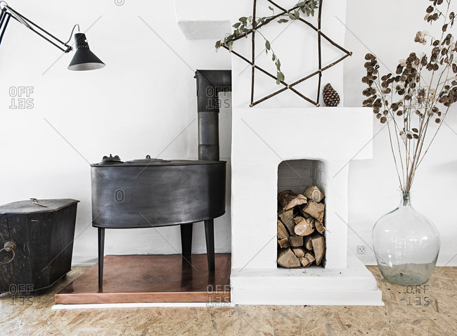 Wood stove and chopped wood in a white room