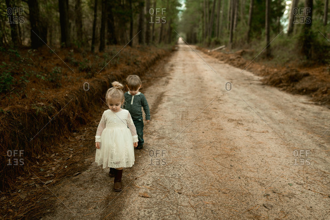 Two Toddlers With Blonde Hair Walking Down A Dirt Road Stock Photo