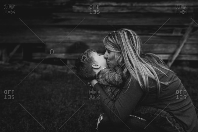Mother kissing toddler boy in black and white