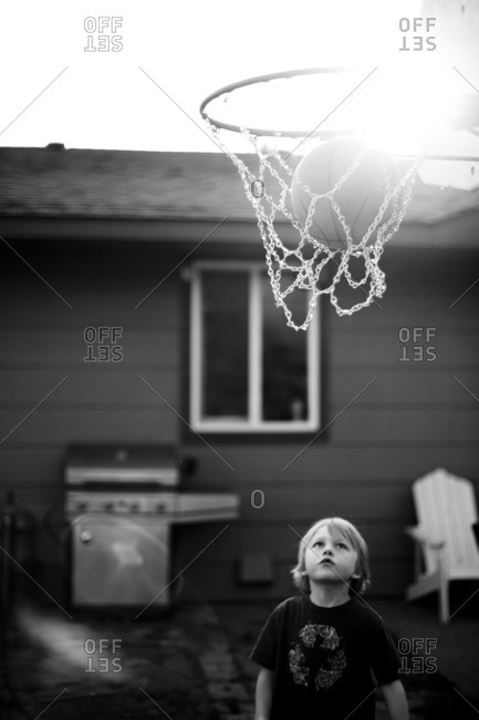 Boy Watching Basketball Go Into Net In Backyard Stock Images