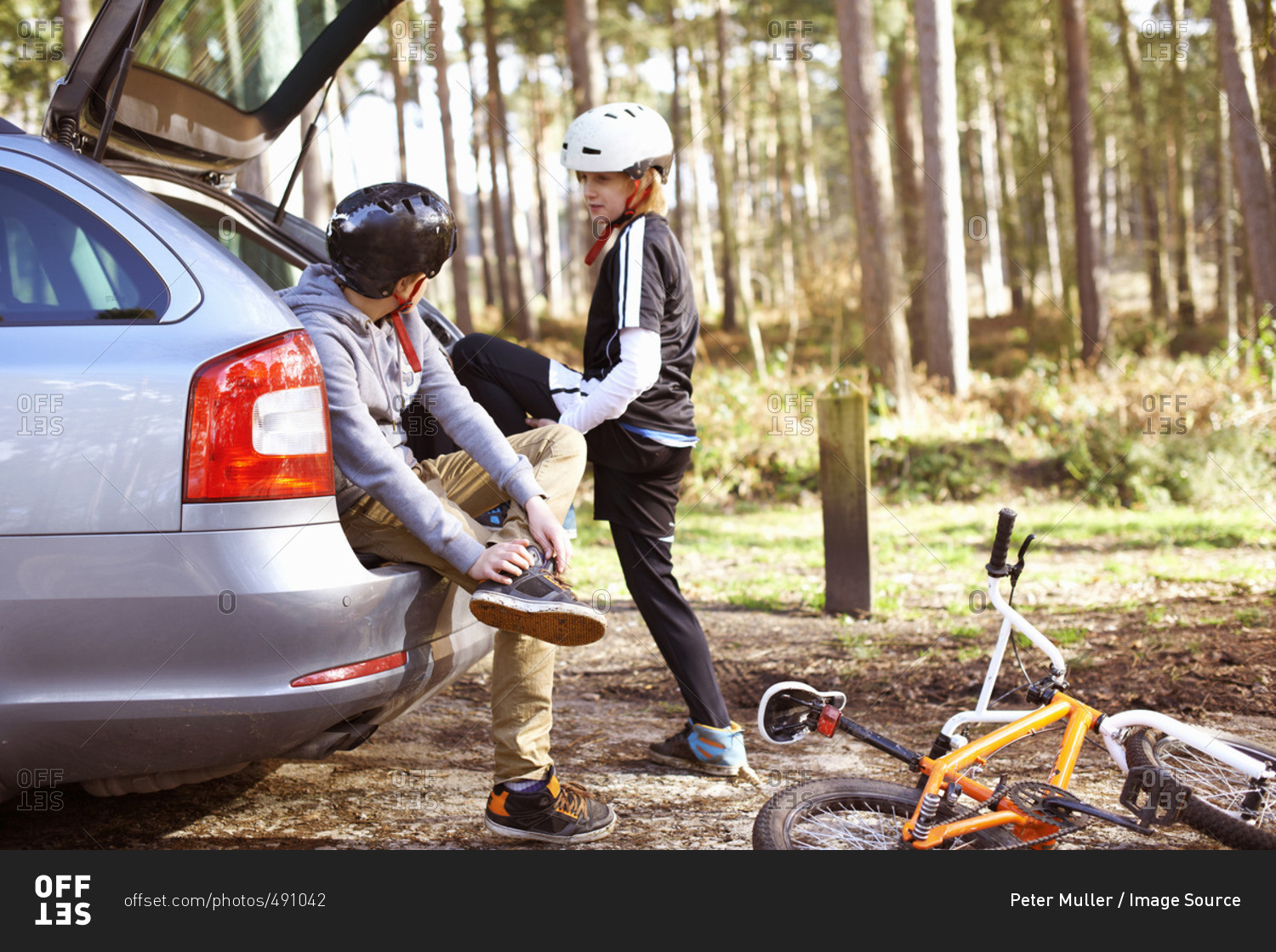 Twin brothers preparing to ride bikes in forest