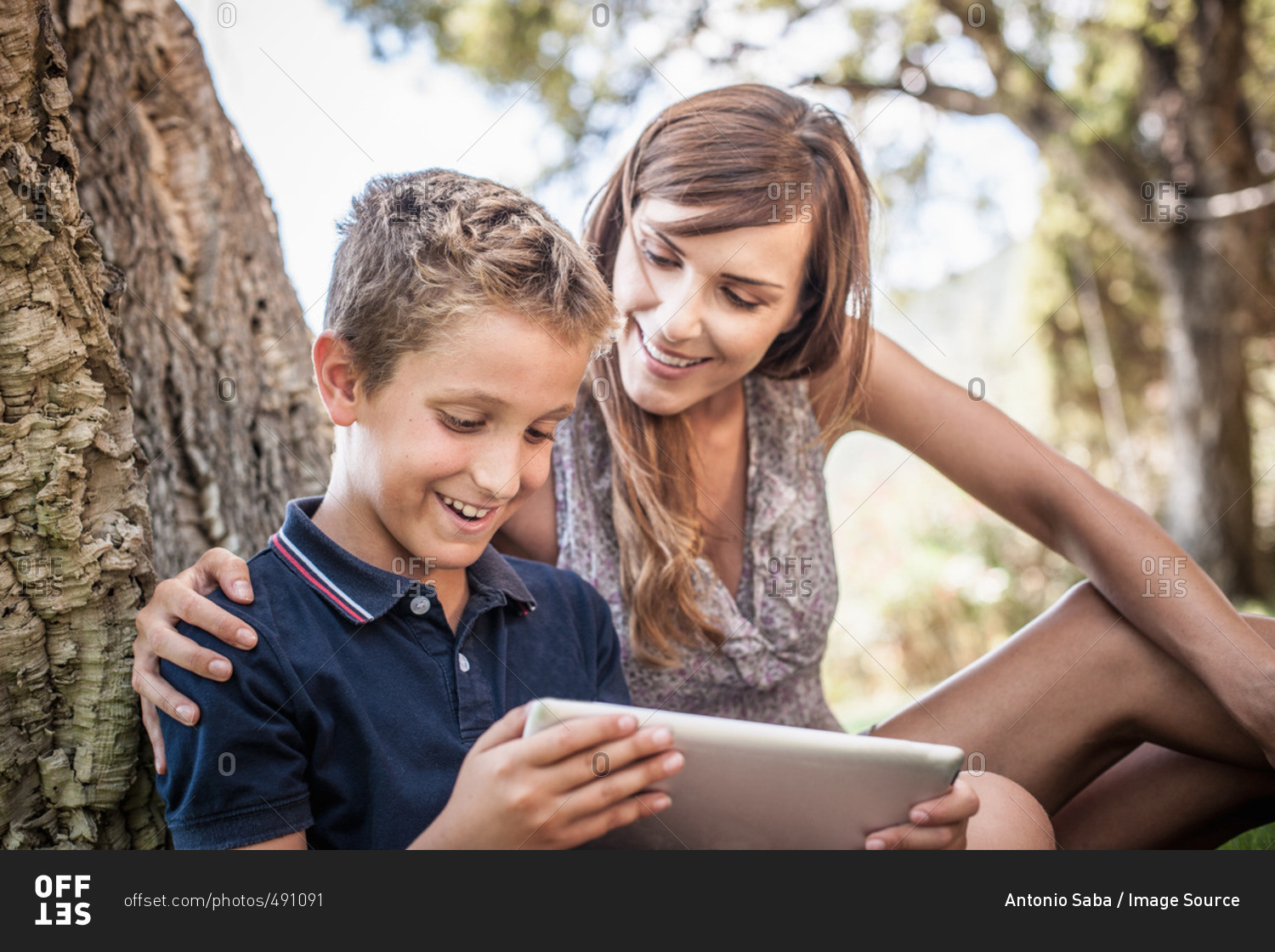 Mother and son looking at digital tablet in holiday home garden, Capoterra, Sardinia, Italy