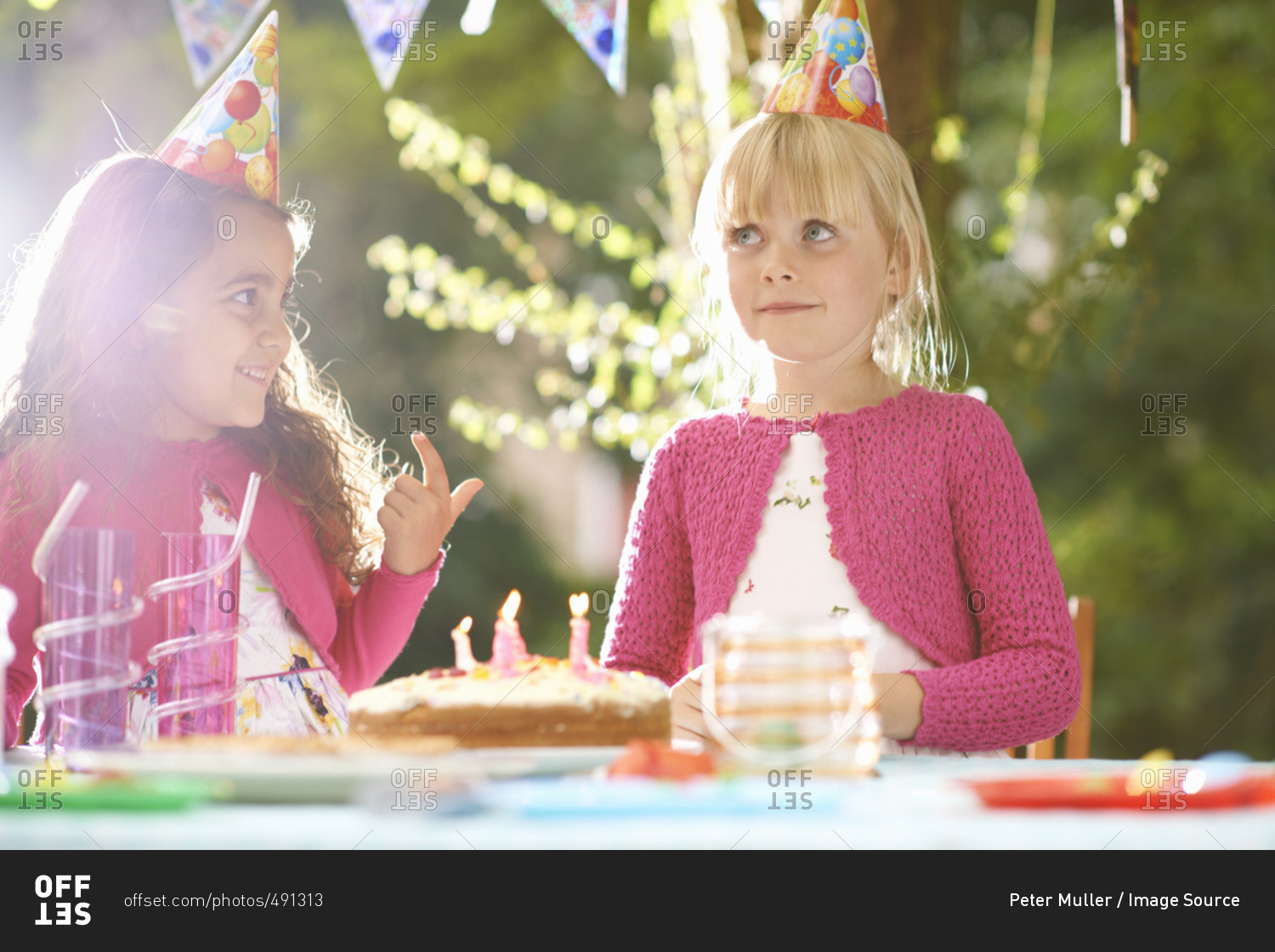 Girls with finger in birthday cake at garden birthday party