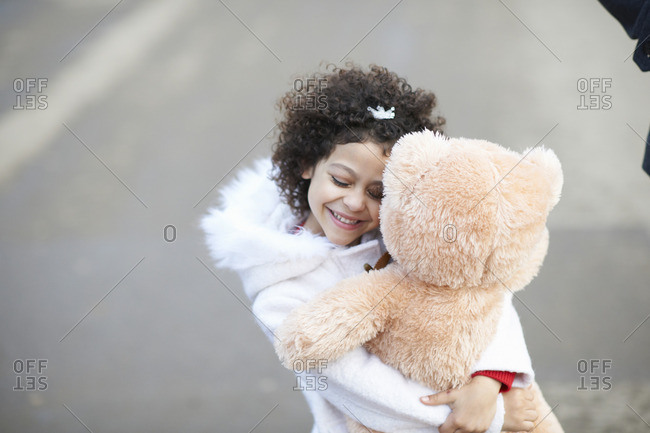 Young girl hugging teddy bear, eyes closed, Stock image