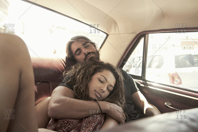 Young couple on road trip asleep in vintage car back seat, Cape Town, South Africa