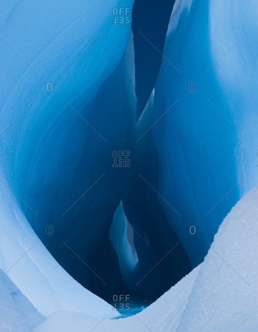 An iceberg with a deep crevasse or fissure, and the contours of melting ice, in Antarctica.