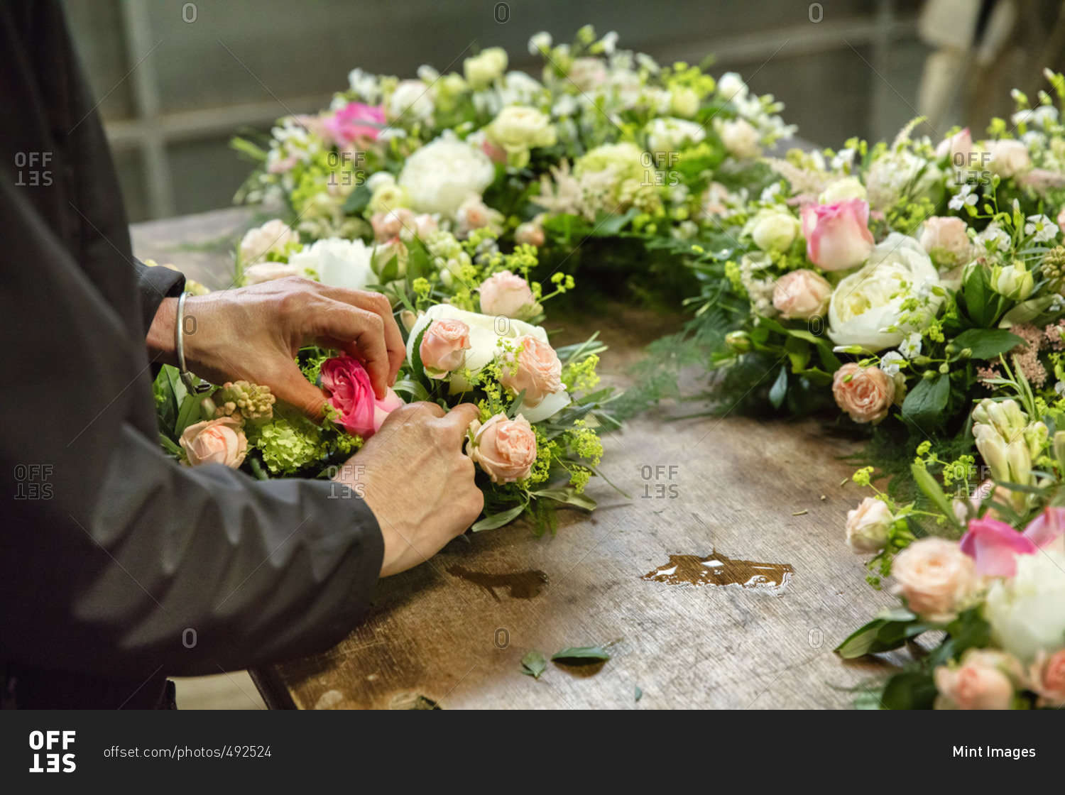 Commercial flower arranging. A florist, a woman working on a floral decoration at a workbench.