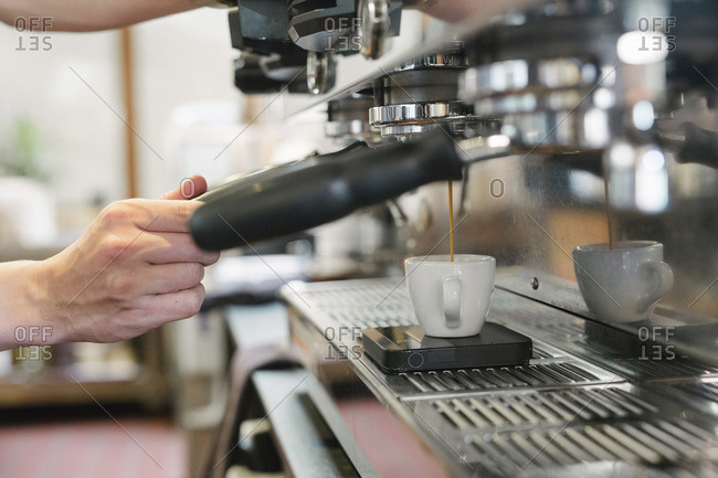 Close up of a man standing in front of an espresso machine, fresh espresso running into a cup.