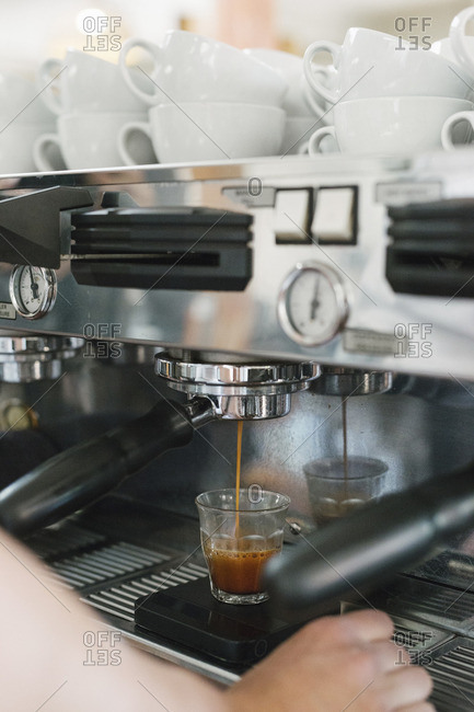 Close up of a man standing in front of an espresso machine, fresh espresso running into a cup.
