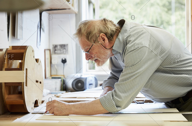 A violin maker at his drawing board drawing out the plans and outline for a new instrument.
