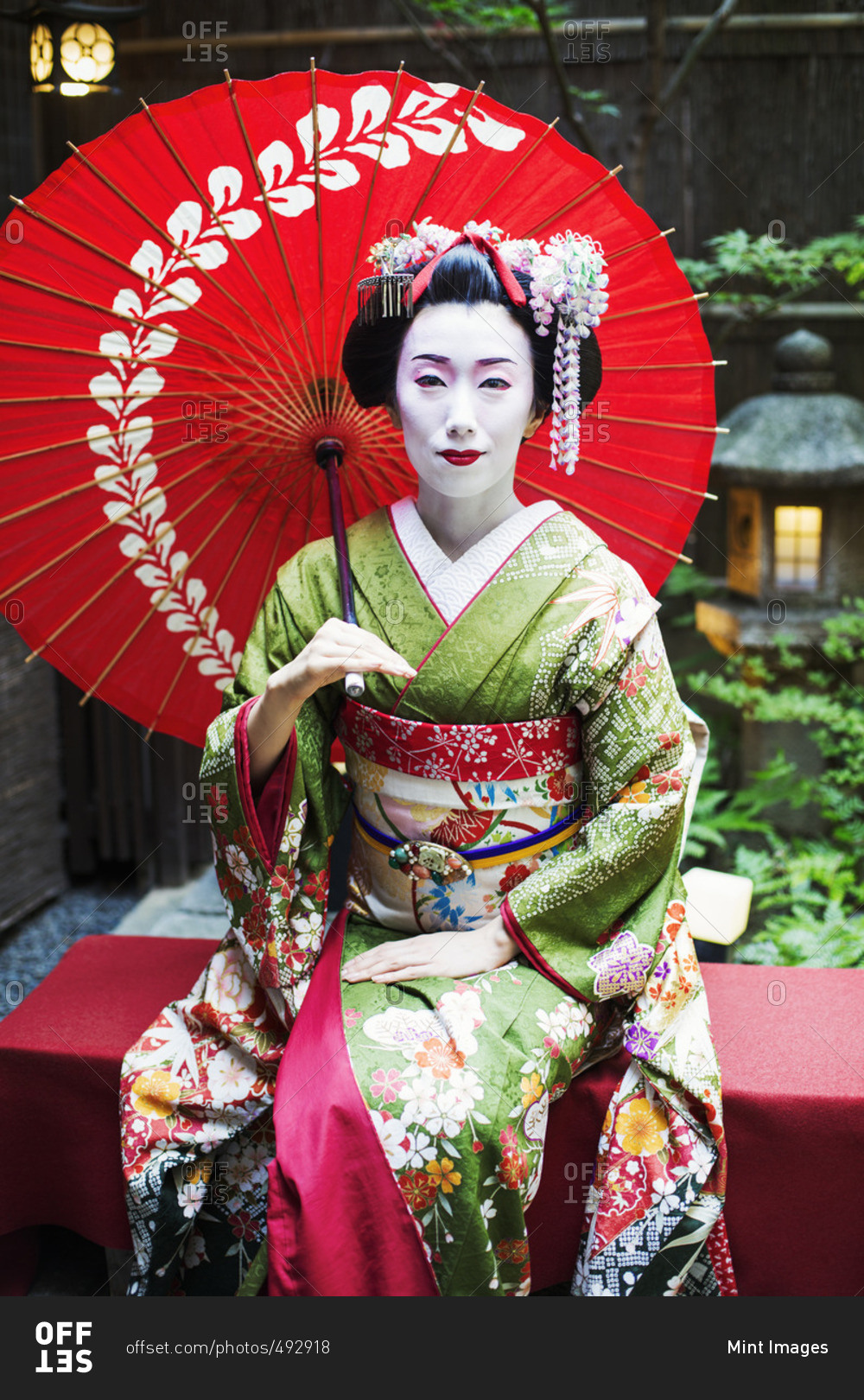 A woman dressed in the traditional geisha style, wearing a kimono and obi  stock photo - OFFSET