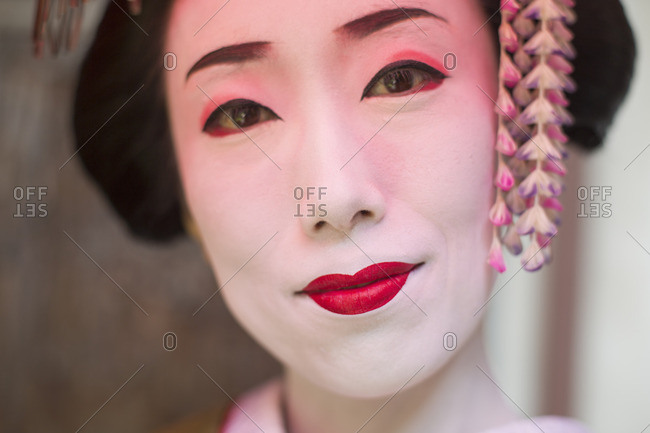 A woman made up in traditional geisha style with an elaborate hairstyle and floral hair clips