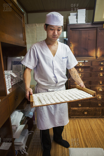 A small artisan producer of specialist treats, sweets called wagashi. A man holding a tray of sweets.