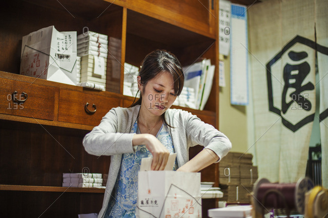 A small artisan producer of specialist treats, sweets called wagashi. A woman working packing sweet boxes for delivery.