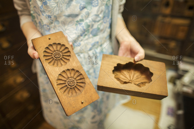 A small artisan producer of specialist treats, sweets called wagashi. A woman holding shaped wooden moulds used in the production of sweets.