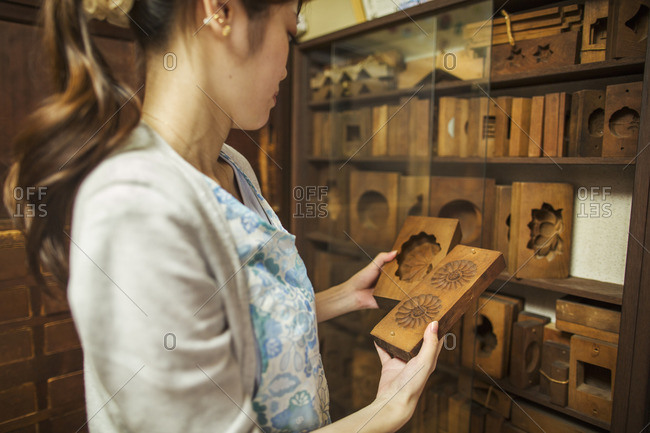 A small artisan producer of specialist treats, sweets called wagashi. A woman holding shaped wooden moulds used in the production of sweets.