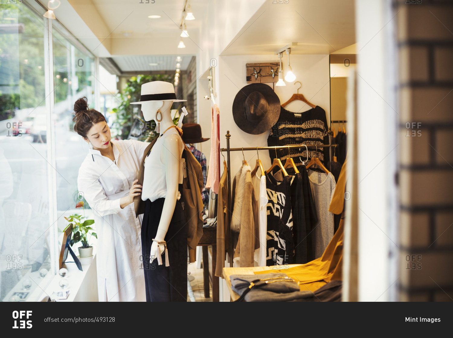 Woman working in a fashion boutique in Tokyo, Japan, dressing a mannequin.