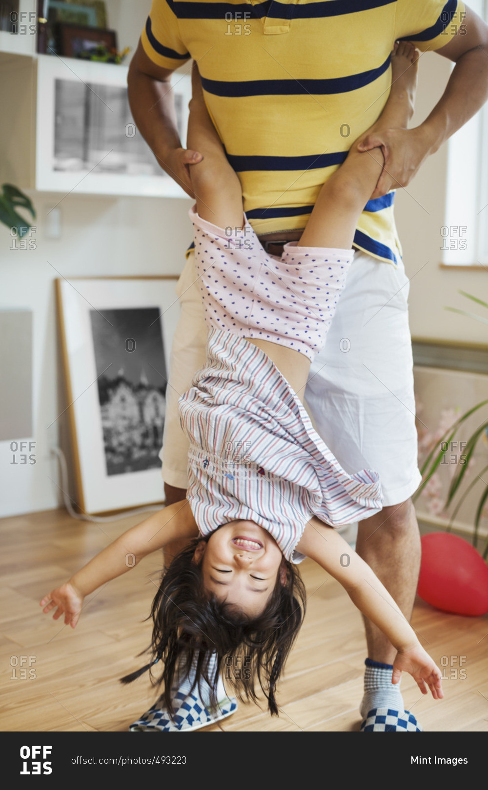 Family home. A man playing with his daughter, holding her upside down.