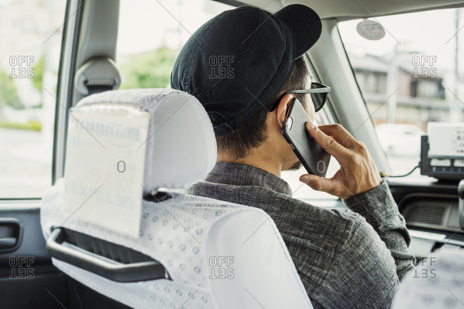A man seated in the passenger seat of a car using his smart phone.