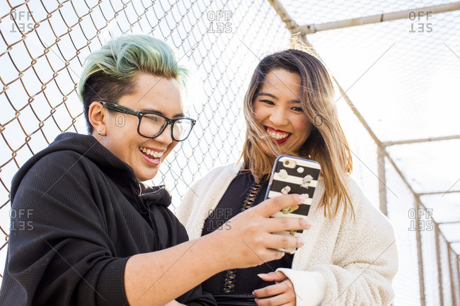Smiling Asian women posing for cell phone selfie