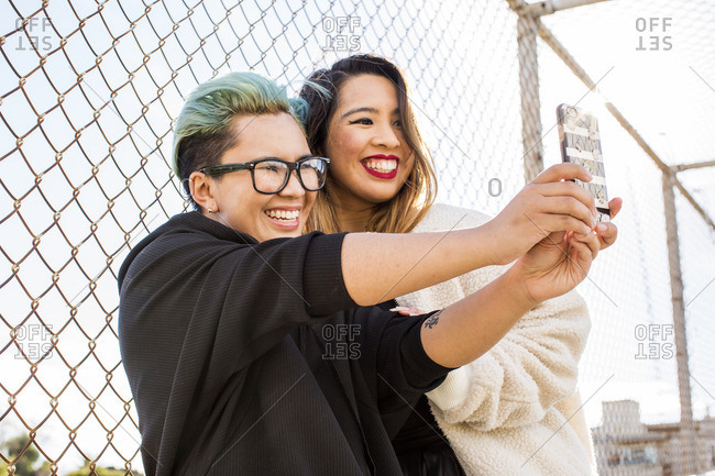 Smiling Asian women posing for cell phone selfie