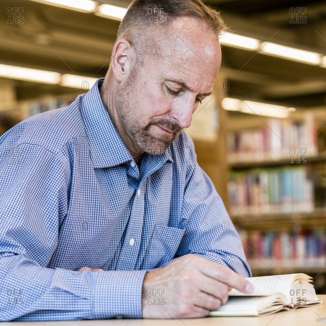 Caucasian man reading book in library