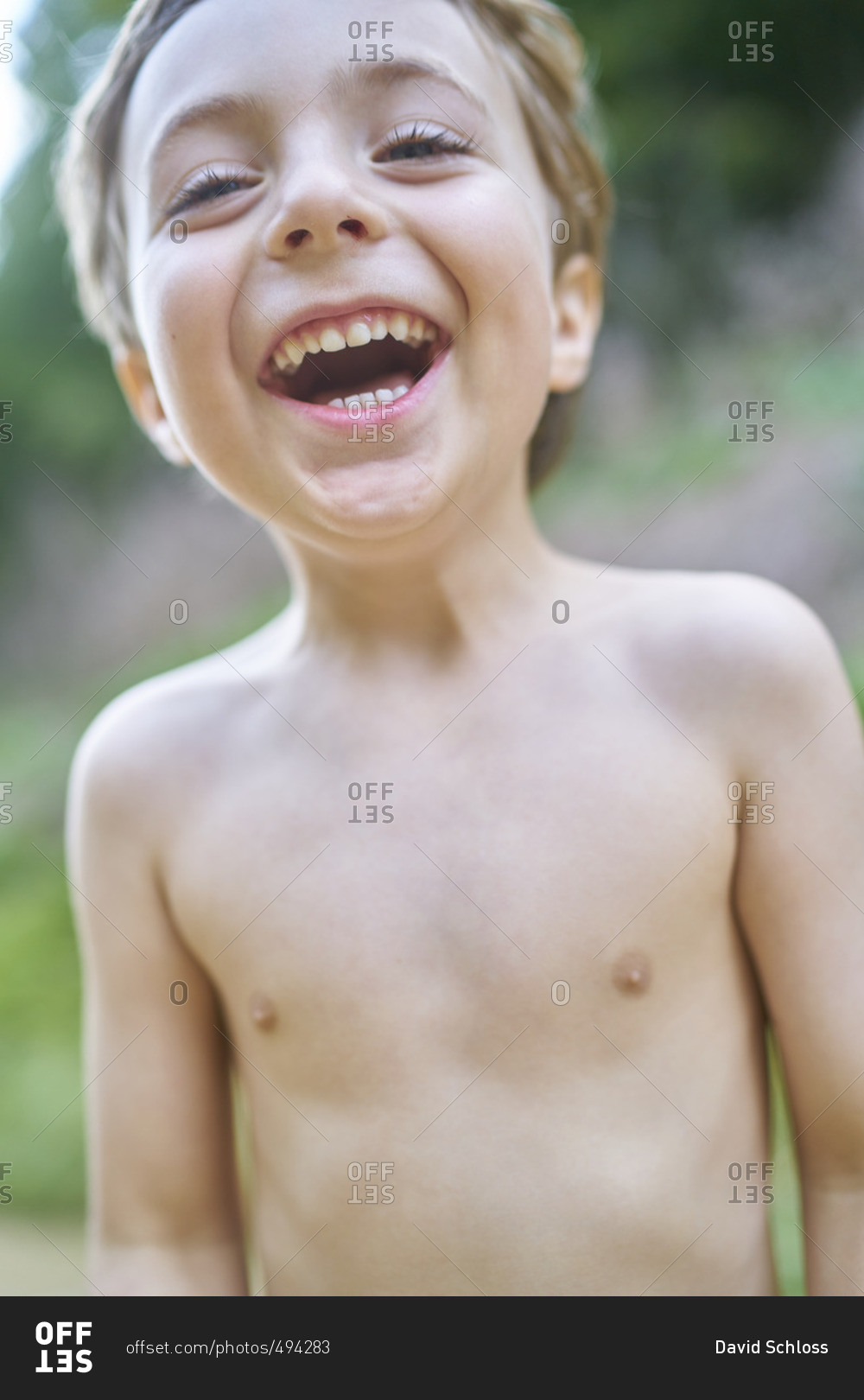 Little boy with brown hair and no shirt laughing at the camera stock ...