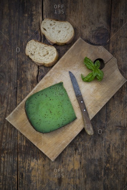 Piece of basil cheese- kitchen knife- slices of white bread and basil leaves on wood
