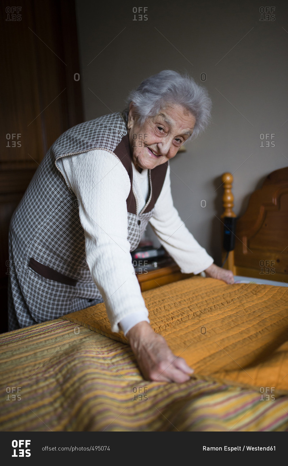 Senior woman putting fresh sheets on a bed